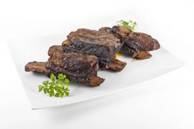 Üç pişmiş dana kaburga ile beyaz dikdörtgen plaka