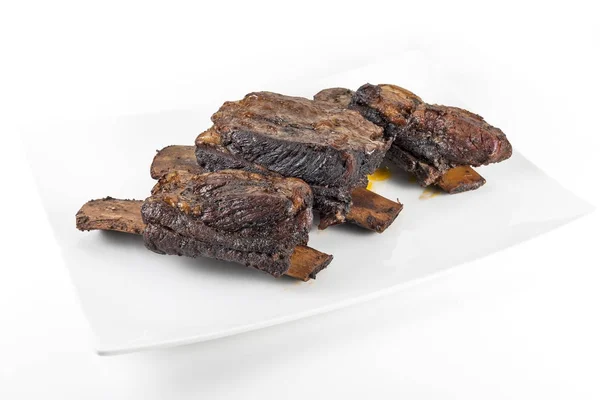 Vit rektangulär platta med tre kokta nötkött revben — Stockfoto