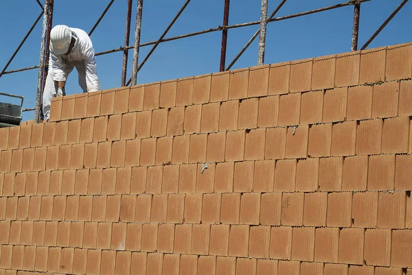 Red brick wall construction with bricklayer in construction site