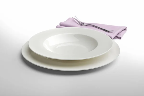Άδειο στρογγυλό λευκό πιάτο και το μπολ με πετσέτα και πιρούνι — Φωτογραφία Αρχείου