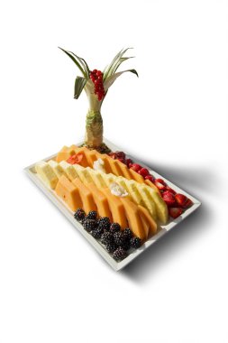 Beyaz arka planda yalıtılmış çilek, böğürtlen, ananas ve kavun dilimleri olan tepsi.
