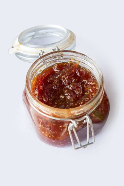 Beyaz zemin üzerinde incir reçeli bulunan kare cam kavanoz