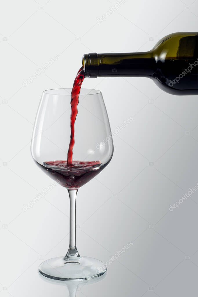 Bottle pouring red wine into an elegant glass isolated with clipping path