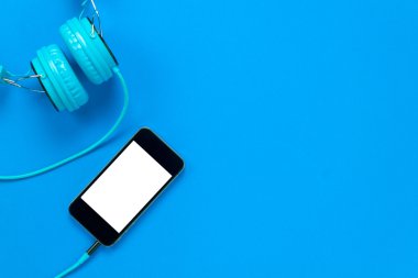 Üstten Görünüm hareket eden telefon ve kulaklık mavi zemin üzerine.