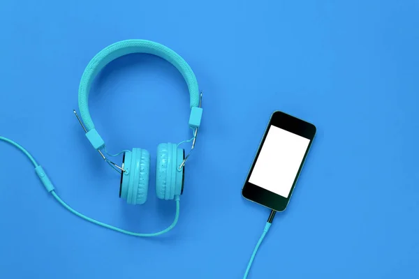 Vista superior del teléfono móvil y auriculares sobre fondo azul . —  Fotos de Stock