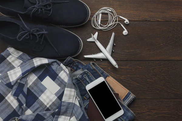 Ovanifrån av tillbehör kläder herrar att resa med teknik bakgrund koncept. Nödvändiga artiklar för resenären eller tonåren och som vuxen förbereda semesterresa. Flera objekt på moderna vit trä. — Stockfoto
