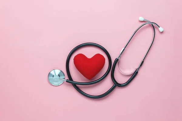 Tablo üstten görünüm düzenleme donanımları tıbbi geçmişi kavramı vurdu. Kırmızı kalp ve stetoskop modern rustik pembe kağıt üzerinde. Doktor hastanede bakım hasta için bir fikir gerekli aksesuarlar.