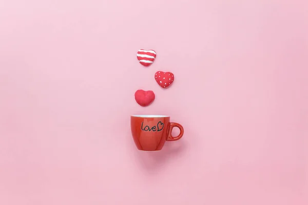 Table top view aerial image of sign valentine\'s day background concept.Flat lay arrangement red coffee cup with steam heart shape on modern pink paper at home office desk studio.Pastel tone design.