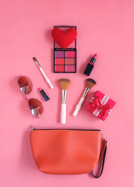 Tablo üstten görünüm Aksesuar giyim kadın tatil arka planda seyahat planlıyoruz. Güzellik ve moda kavramı. El çantası pembe kağıt modern birçok temel öğeleri kozmetik ve güneş gözlüğü ile düz lay.