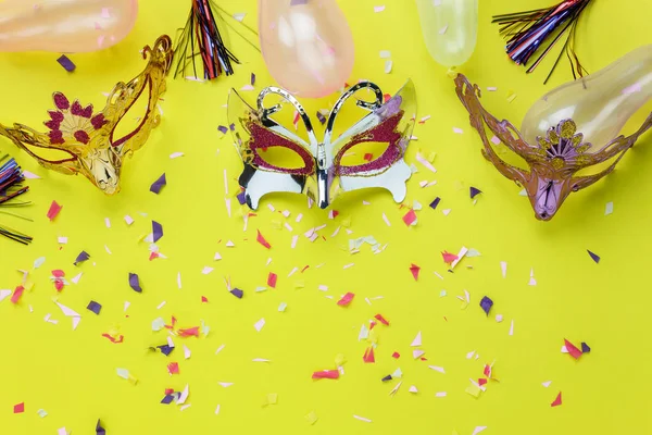 Table top view aerial image of beautiful colorful carnival mask background.Flat lay accessory object on modern yellow paper at home office desk studio.Creative design text for the festival backdrop.