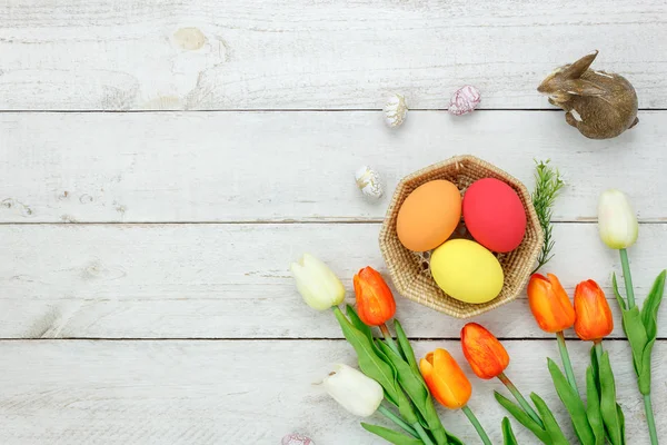 Table top view shot of arrangement decoration Happy Easter holiday background concept.Flat lay colorful bunny egg with tulip flower and rabbit doll on modern rustic white wooden at home office desk.