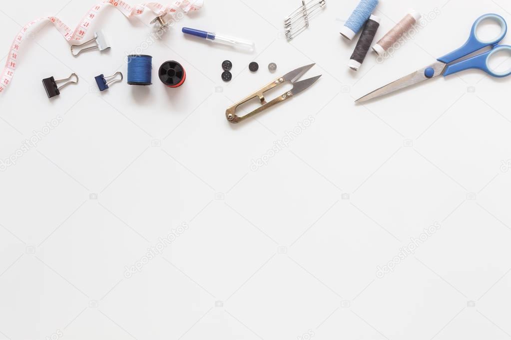 Flat lay aerial image of fashion designer items background concept.Top view sewing accessory or tailor equipment on modern rustic white paper at home office desk studio.Crafting tools in work shop.