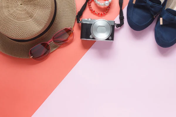 Tablo üstten görünüm Aksesuar giyim kadın tatil arka planda seyahat planlıyoruz. Güzellik ve moda kavramı. Pembe kağıt modern birçok temel öğeleri kostüm ve güneş gözlüğü ile fotoğraf makinesinin düz lay.