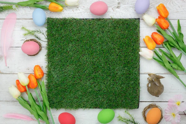 Tablo üstten görünüm süslemeleri mutlu Paskalya tatili arka plan kavramı bir kadeh. Düz bunny yumurta tulip çiçek Ofis Masası, modern rustik beyaz üzerine yatırın. Kadar de sahte için yeşil çim tasarım alanı boş.