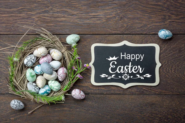 Table top view shot of decoration Happy Easter holiday background concept.Flat lay bunny egg with blossom at bird\'s nest on modern brown wooden at office desk. blackboard design text welcome to season