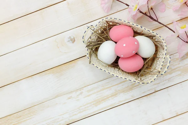 Table top view shot of arrangement decoration Happy Easter holiday background concept.Flat lay colorful bunny egg with pink blossom on brown sackcloth at home office desk.Space for creative design.