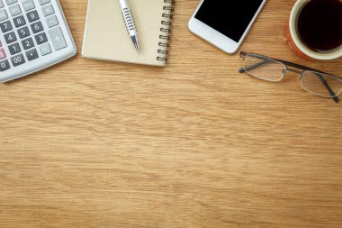 Tablo üstten görünüm havadan görüntü ofis Resepsiyon arka plan kavramı üzerinde sabit. Düz nesneleri temel aksesuarıyla kahve fincan yatıyordu. Modern kahverengi ahşap ev stüdyosunda öğeleri. İçin alan metin eklemek.