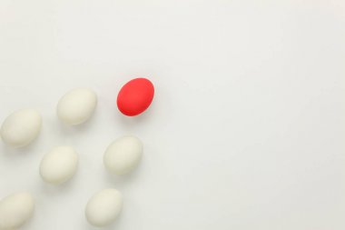 Tablo üstten görünüm hava iş ya da görüntü mutlu Paskalya tatili arka plan kavramı. Düz kırmızı yumurta üstün veya lider gemi diğer beyaz yumurta beyaz kağıt modern zemin üzerinde yatıyordu. Nesneyi farklı diğer.