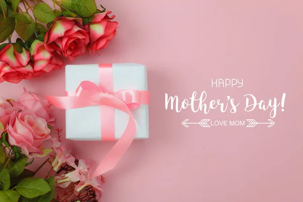 Top view aerial image of decoration Happy mothers day holiday background concept.Flat lay white gift box with red rose on modern beautiful pink paper at home office desk.Free space for design text.
