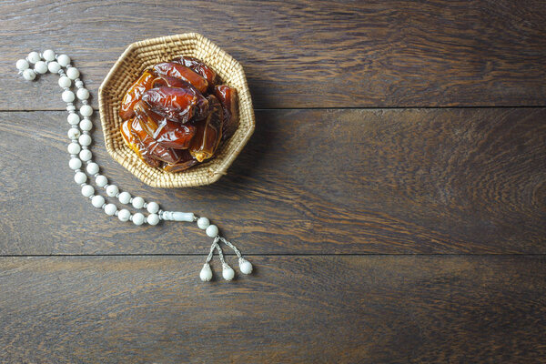 Вид сверху стола аэрографическое изображение декора праздничного задника Рамадан Карим. Плоская дата в деревянной корзине с белым цветом на современном ржаво-коричневом дереве на рабочем столе.
.