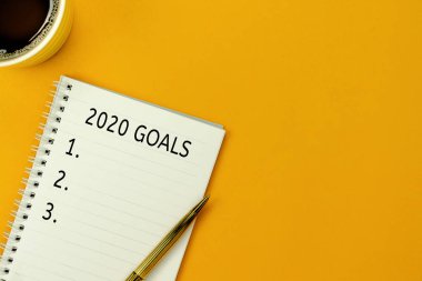 2020 yılının hava görüntüsü KPI hedefleri ve planları. Sarı kağıt üzerine temel nesnelerin düzlüğü. Not defterine ve kalem üzerine aksesuar bürosu için metin & arkaplan arkaplanı kopyala.