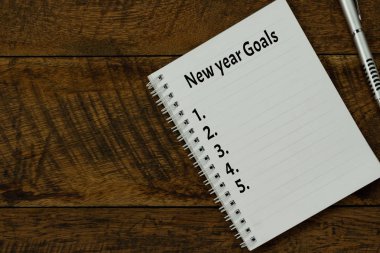 2020 Yeni Yıl İş Hedefleri ve Planları 'nın yukarıdaki görüntüsü. Temel objenin düz uzantısı kahverengi ahşap üzerine. Not defterine siyah kahve ve kalem ile aksesuar bürosu masa arkası için metin