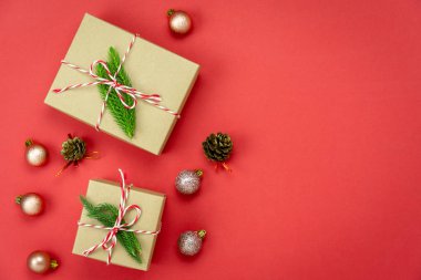 Merry Christmas dekorasyon ve mutlu yeni yıl süsleri kavramı en iyi görünümünü masa. Düz yatıyordu temel fark nesneleri hediye kutusu ve köknar ağacı ev stüdyosu ofis masası, kırmızı kağıt modern arka plan üzerinde.