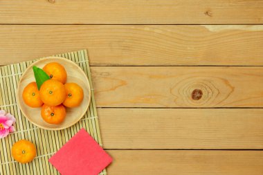 Tablo üstten görünüm ay yeni yıl ve Çin yeni yıl tatili kavramı arka plan. Ahşap sepet ve pembe kiraz çiçeği kırmızı harçlık ve süslemeleri üzerinde modern rustik kahverengi zemin ile düz yatıyordu turuncu