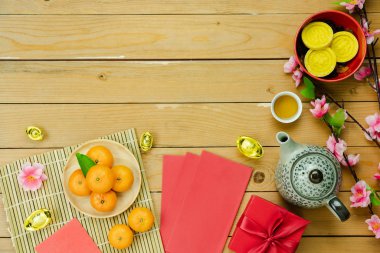 Tablo üstten görünüm ay yeni yıl ve Çin yeni yıl tatili kavramı arka plan. Ahşap sepet ve pembe kiraz çiçeği kırmızı harçlık ve süslemeleri üzerinde modern rustik kahverengi zemin ile düz yatıyordu turuncu