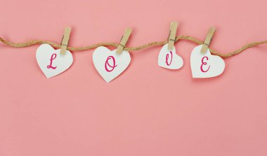 Sevgililer Günü arkaplan kavramının hava görüntüsü. Aşk metni halat iplerinde asılı. Düz, modern kırsal pembe kağıt üzerinde yatıyor.Pastel tonlar. Mevsim için el yapımı işaret ile oluşturulan eşyalar.