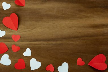 Masa üstü görüntü dekorasyonu Sevgililer Günü arka plan kavramının havadan görüntüsü. Düz, yaratıcı tasarım için modern kırsal kahverengi ahşap üzerinde kesilmiş rengarenk aşk şekilli kağıt parçaları yatıyordu..