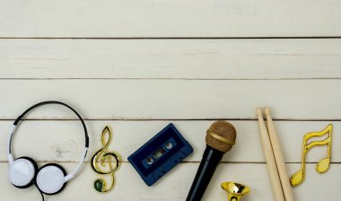 Müzik enstrümanı araçları kavramının en üst görünümü arka plan. Müzisyen veya parti teçhizatı için şarkı söylemek için işaret tablosu. Mikrofon nota teybi kaset ve modern beyaz ahşap baget.