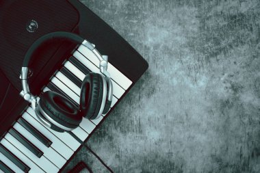 Müzik enstrümanı araçları kavramının en üst görünümü arka plan. Müzisyen veya parti ekipmanları için şarkı söylemek için tabela düzlüğü. Modern gri çimentoda kulaklık ve elektrikli piyano. Yaratıcı tasarım için alan.