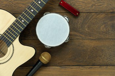 Müzik enstrümanı araçları konseptinin en üst görünümü arka plan. Müzisyen veya parti ekipmanları için şarkı söylemek için tabela düzeyi. Yaratıcı tasarım için ortam ve modern ahşap üzerinde set mikrofonlu bateri ve gitar..