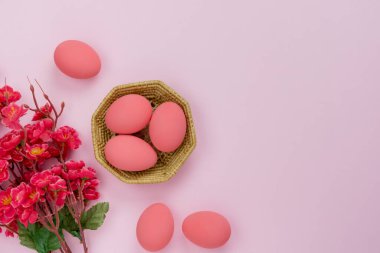 Dekorasyonun üst görünümü & sembolü Mutlu Paskalya bayramı arka plan kavramı. Düz, ev ofis masasındaki modern güzel pembe kağıdın üzerine aksesuar tavşan yumurtaları ve çiçekleri serer. Tasarım için boş alan.
