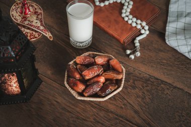 Ramazan Kareem tatil arkaplanının hava görüntüsü. Tespih ve aydınlatma ve çay fincanı ile düz bir tarih. Oruç için hazırlanan helal yemek, siyah ahşap üzerinde yaşayan Müslümanlar için zorunludur..