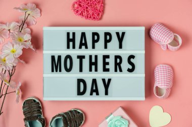 Dekorasyonun gökyüzü görüntüsü Mutlu Anneler Günü metin arkaplan kavramı. Bebek ayakkabılı düz konum hediye kutusu ve modern pembe kağıt üzerinde aşk biçimli çiçek. Tasarım için kopyalama alanı..