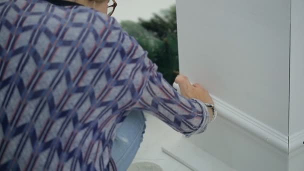 Blonde woman glue plinth on white column in house in new year eve — Stock Footage Blonde woman glue plinth on white column in house in new year eve Royalty Free Stock Footage