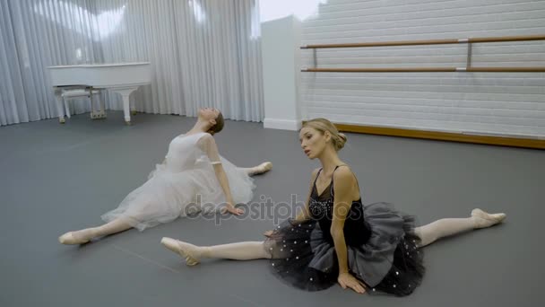Two beautiful ballerinas sit on twine on floor in ballet school. — Stock Footage Two beautiful ballerinas sit on twine on floor in ballet school. Video Clip