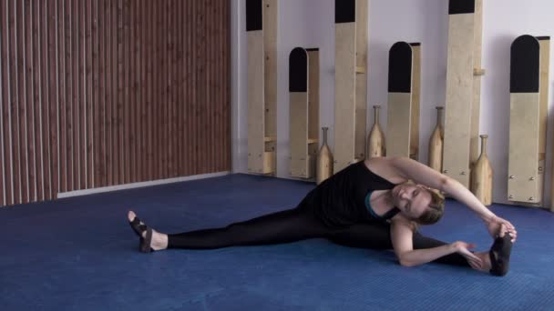 Woman sits on twine and performs an inclination forward for stretching body. — Stock Footage Woman sits on twine and performs an inclination forward for stretching body. Stock Video