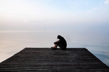 Hayal kırıklığına uğramış depresyon adam ahşap köprü üzerinde oturan Hood