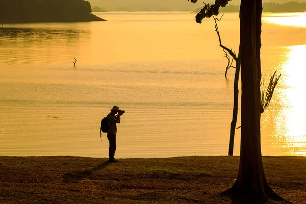 Silhueta de fotógrafo tirando uma foto perto do lago . — Fotografia de Stock