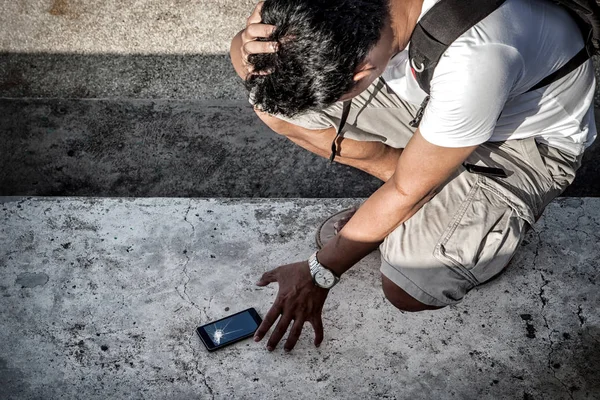 Homme saisir un smartphone cassé avec écran écrasé sur le sol en béton . — Photo