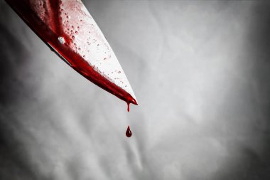 close-up of man holding knife smeared with blood and still dripping. clipart