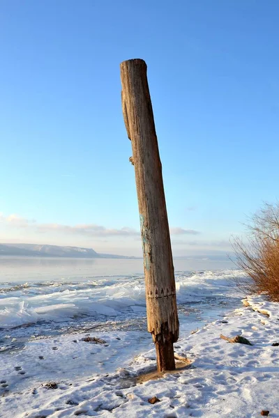一个孤立无援的柱子在海浪中 在沙滩上的沙滩上挖着 — 图库照片
