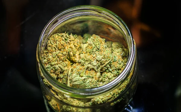 Germogli di fiori di cannabis in vaso di vetro sullo sfondo scuro — Foto Stock