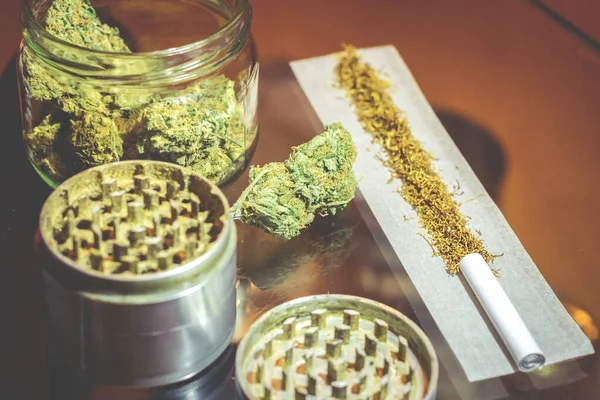 Kannabis kuncup bunga dalam botol kaca dengan penggiling dan tembakau dalam sendi — Stok Foto