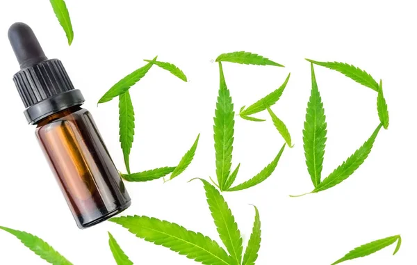 Cannabis Feuilles sur blanc formant des lettres CBD et bouteille de compte-gouttes d'huile CBD — Photo
