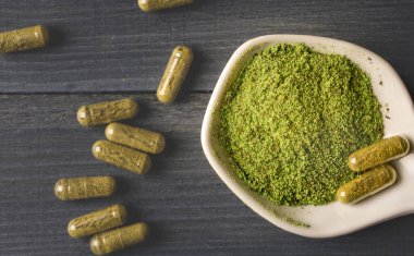 Seramik kaşık ve Kratom kapsüllerindeki Kratom tozunun üst görünümü