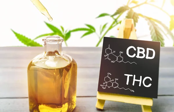Huile de cannabis en bouteille de verre et tableau avec dessin moléculaire de THC et CBD — Photo